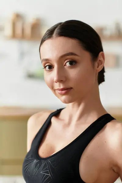 Beautiful young woman dressed in black sportswear exercises actively in her modern apartment. — Stock Photo