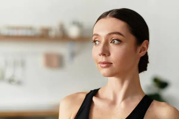 Belle jeune femme exerce en tenue de sport noire dans son espace de vie contemporain. — Photo de stock