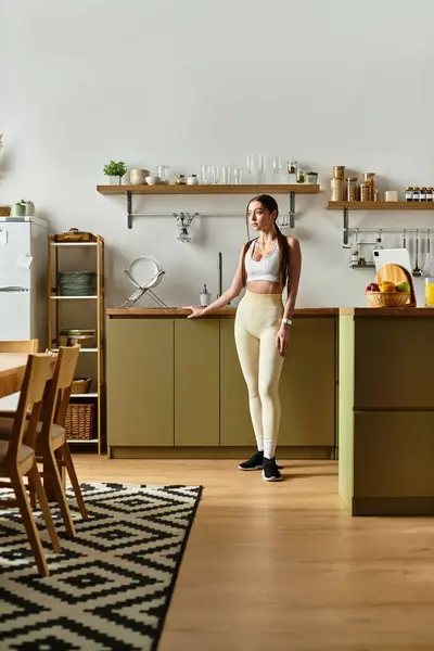 A beautiful young woman standing in a stylish, modern kitchen, radiating happiness. — Stock Photo