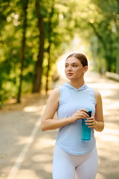 La luz del sol fluye a través de los árboles mientras una joven mujer camina, refrescando su espíritu. - foto de stock