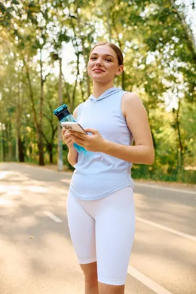 Sporty woman stands confidently on a path, ready for her workout in the sun. — Stock Photo