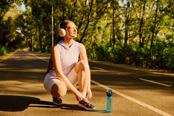 Beautiful athletic woman crouches down to tie her shoelaces during a sunny workout session. — Stock Photo