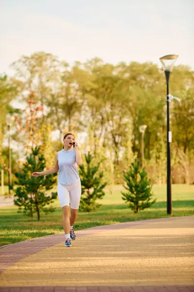 A young woman jogs in a peaceful park, surrounded by trees, savoring nature. — Stock Photo