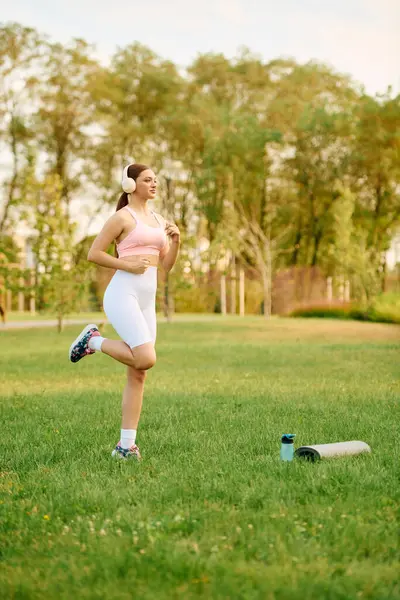 A vibrant young woman jogs gracefully in a sunny park, enjoying fitness and nature. — Stock Photo