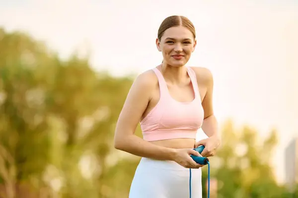 Bright sunshine highlights a beautiful athletic woman as she prepares for her workout with a rope. — Stock Photo