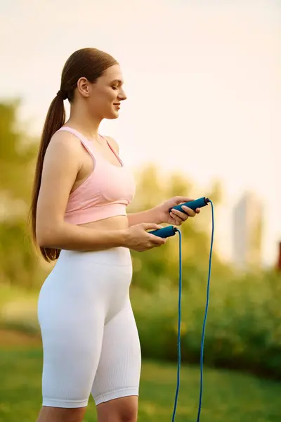 Sporty woman engages in energetic workout, focusing on jumping rope while enjoying the sunset glow. — Stock Photo