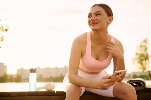 Beautiful athletic woman relaxes by the water after an energizing workout during golden hour. — Stock Photo