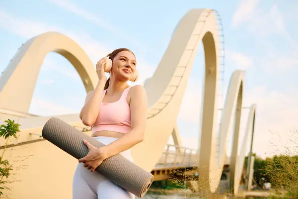 Young athletic woman listens to music while preparing for yoga practice in a scenic setting. — Stock Photo