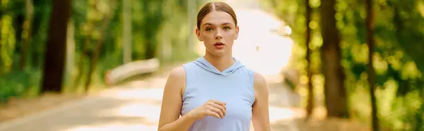Giovane donna atletica corre energicamente su un tranquillo sentiero forestale circondato da alberi verdi. — Foto stock