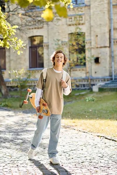 Brightly dressed young man walks with a skateboard, smiling under the warm sun in a park. — Stock Photo