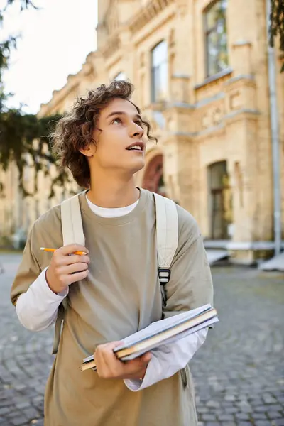 A stylish young man with a notebook stands outside an old building, contemplating nature. — Stock Photo