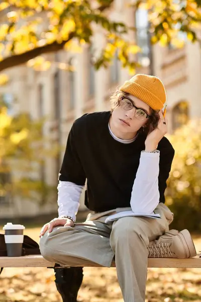 Stylish student sits on a bench, deep in thought, surrounded by autumn foliage in a peaceful area. — Stock Photo