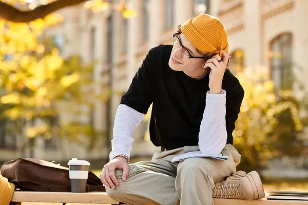A stylish man sits pensively outside, surrounded by golden autumn leaves, studying. — Stock Photo