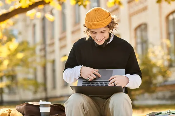 Handsome student immersed in laptop activity, surrounded by colorful autumn leaves and sunlight. — Stock Photo
