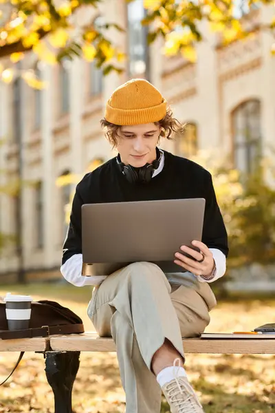 Handsome young man with stylish attire focused on his laptop while enjoying nature outside. — Stock Photo
