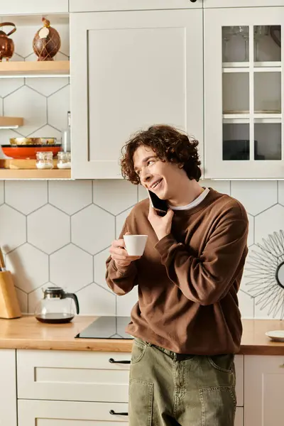 A young student in a brown sweatshirt chats happily while holding a cup, surrounded by home decor. — Stock Photo