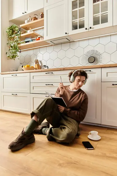 In a cozy modern apartment, a young student writes in a notebook while enjoying coffee. — Stock Photo