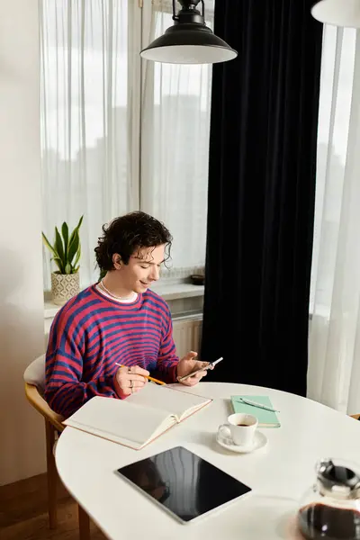 Lively young person engages with their phone while studying in a stylish home setting. — Stock Photo