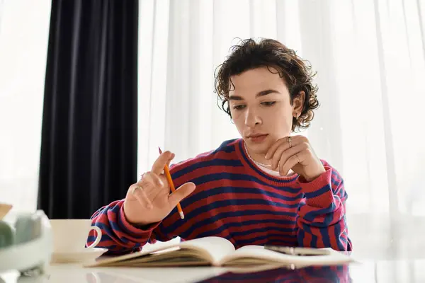 A young person in a striped sweatshirt studies at home, bathed in natural light. — Stock Photo