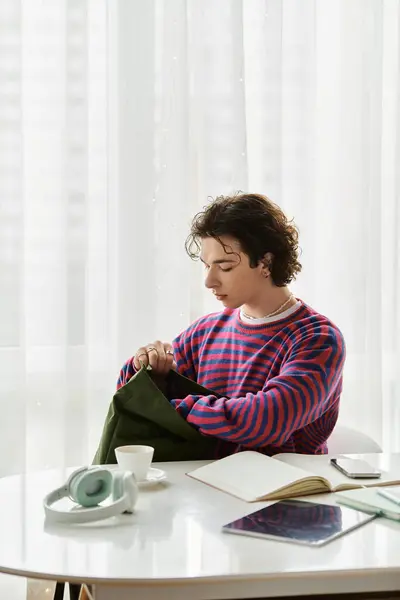In a vibrant striped sweatshirt, a young non binary individual relaxes in their stylish home. — Stock Photo