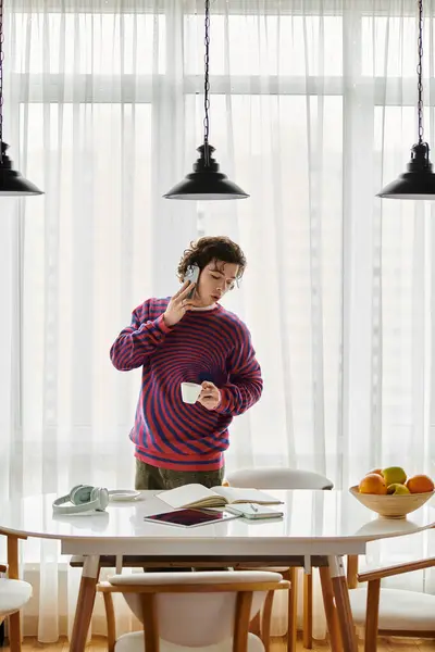 In a bright, stylish apartment, a young non binary person sips coffee while reflecting on life. — Stock Photo
