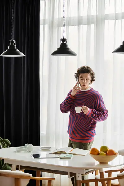 In a modern apartment, a young non binary person savors coffee while surrounded by fresh fruit. — Stock Photo