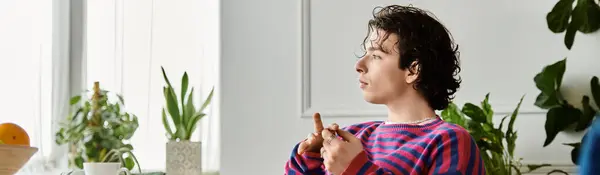 A young non binary individual in a striped sweatshirt relaxes in a modern living space, banner — Stock Photo