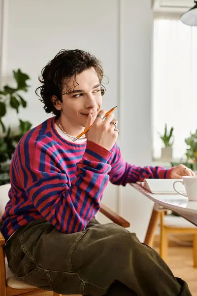 Un jeune non binaire réfléchit tout en étudiant dans un sweat-shirt rayé coloré. — Photo de stock