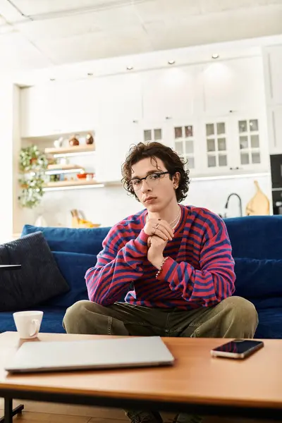 Une jeune personne non binaire s'assoit confortablement dans un sweat rayé vibrant, reflétant la créativité. — Stock Photo