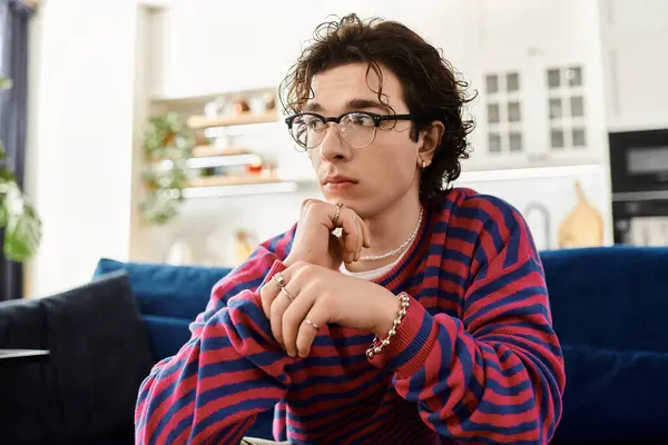 This young, non binary person in vibrant stripes contemplates life in their chic living space. — Stock Photo