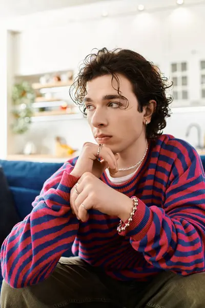 A non-binary person with curly hair relaxes in their stylish apartment, deep in thought. — Stock Photo
