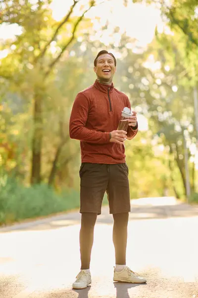 Hombre tatuado posa felizmente en un atuendo casual, rodeado de naturaleza otoñal. - foto de stock