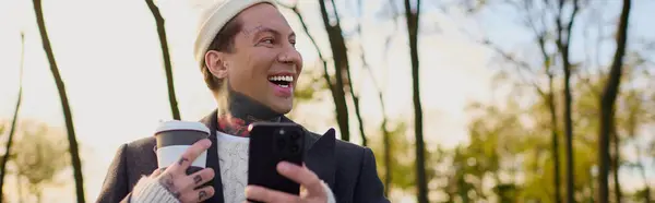 Handsomeness shines through as a trendy man with tattoos smiles joyfully while holding coffee. — Stock Photo