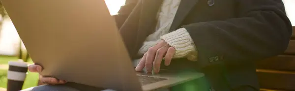 Smartly dressed young man with tattoos types on his laptop while seated in a park under sunlight. — Stock Photo