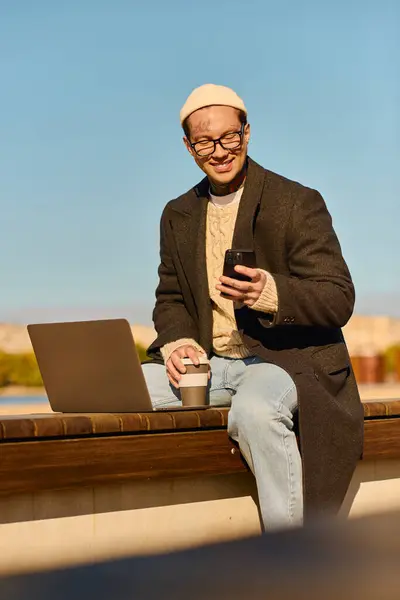 Handsome young man with glasses smiles while holding a phone outdoors, blending work and leisure. — Stock Photo