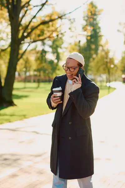 Handsome man with tattoos smiles as he chats on his phone, dressed in trendy attire. — Stock Photo