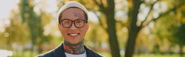 Handsome man poses with a bright smile in a vibrant outdoor park during golden hour. — Stock Photo