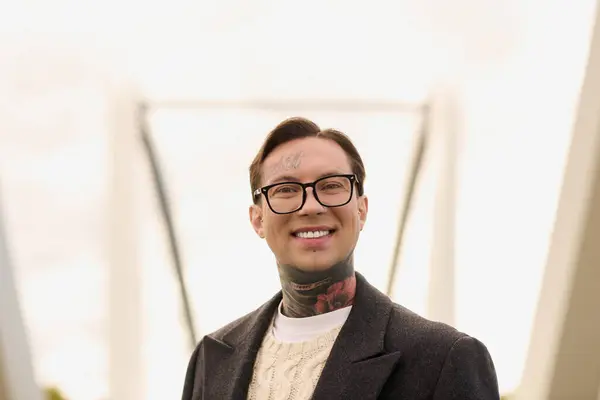 Young man with tattoos poses confidently in trendy outfit, surrounded by striking architecture. — Stock Photo