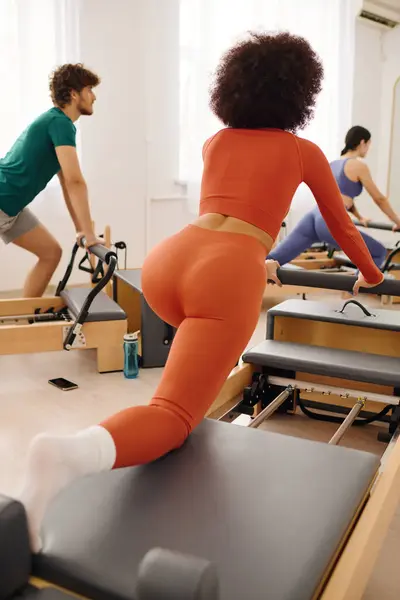 Participants strengthen their bodies with pilates reformers in a spacious studio. — Stock Photo