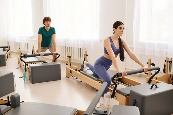 Participants engage in an invigorating pilates workout in a spacious, well lit studio. — Stock Photo