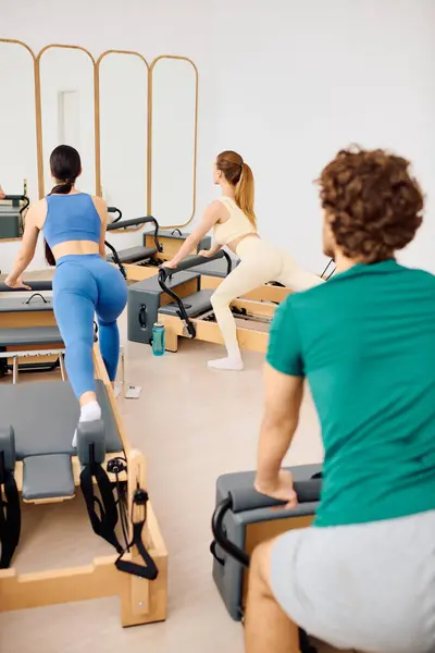 Three fitness lovers practice pilates with enthusiasm in a bright, elegant studio setting. — Stock Photo