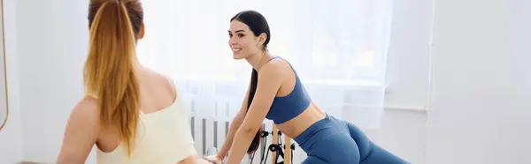 Duas mulheres se fortalecendo e flexionando em um estúdio ensolarado durante uma aula de Pilates energizante. — Fotografia de Stock