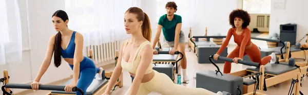 Participants focus intensely while performing challenging pilates exercises in a spacious studio. — Stock Photo