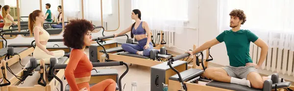 Participants perform stretching exercises on reformer machines in a spacious pilates studio. — Stock Photo