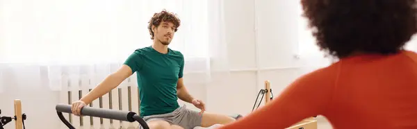 Двоє людей практикують пілатес у добре освітленій студії, наповненій енергією та мотивацією. — стокове фото