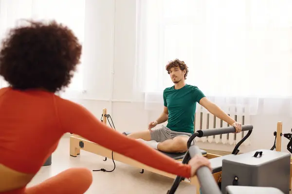 Two people practice pilates in a bright, spacious studio, demonstrating their skills and focus. — Stock Photo