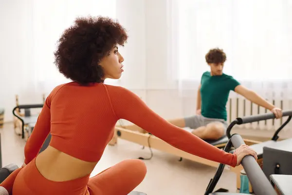 Two people practice pilates, enhancing strength and flexibility in a bright studio. — Stock Photo