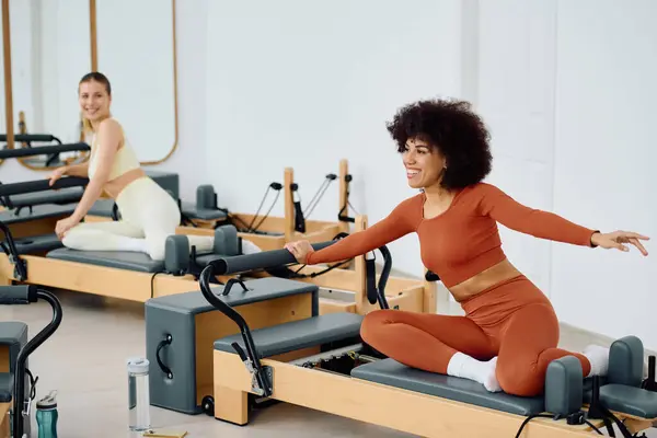 Two enthusiastic individuals engage in an energetic pilates workout, smiling and connecting. — Stock Photo
