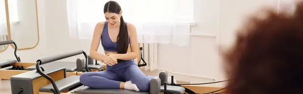 A dedicated person stretches on a reformer in a bright, inviting studio. — Stock Photo