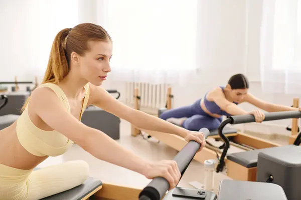 Focused individuals engage in pilates workouts using reformer machines in a modern studio. — Stock Photo